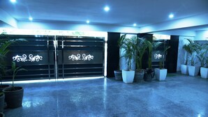 A spacious lobby with a polished floor, decorative metal gates, and several potted plants. - Pacific Inn Sec. 46 (Gurugram)