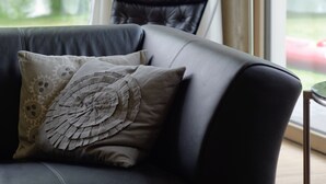 A modern living room with a black leather sofa, decorative pillows, and a floor lamp. - House on the Havelbogen directly on the water with canoe and jetty, garden apartment***** (Werder (Havel))