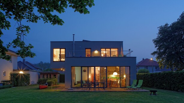 A modern two-story house with a large glass front, a visible kitchen area, and a well-maintained lawn. - House on the Havelbogen directly on the water with canoe and jetty, garden apartment***** (Werder (Havel))