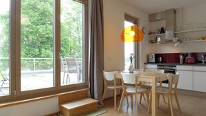 A modern kitchen with white cabinets, a dining table with chairs, and a large window with curtains. - House on the Havelbogen directly on the water with canoe and jetty, terrace apartment***** (Werder (Havel))