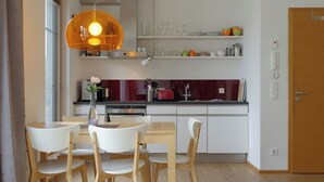 A modern kitchen with white cabinets, a wooden dining table, and chairs. - House on the Havelbogen directly on the water with canoe and jetty, terrace apartment***** (Werder (Havel))