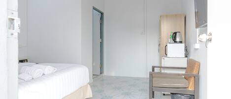 A hotel room with a bed, a chair, a small table, and a television.