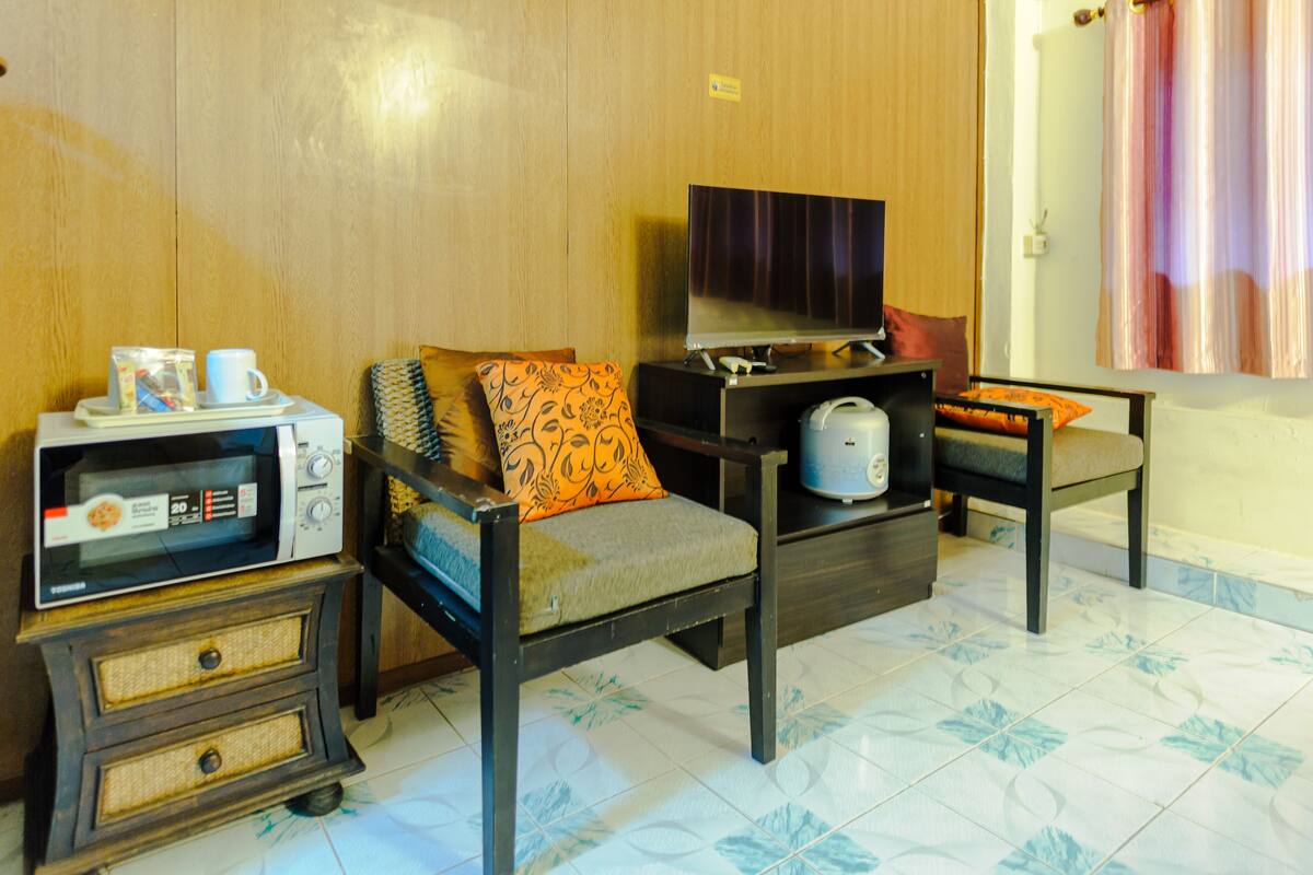 A living room with a sofa, a television, a microwave, and a kettle.