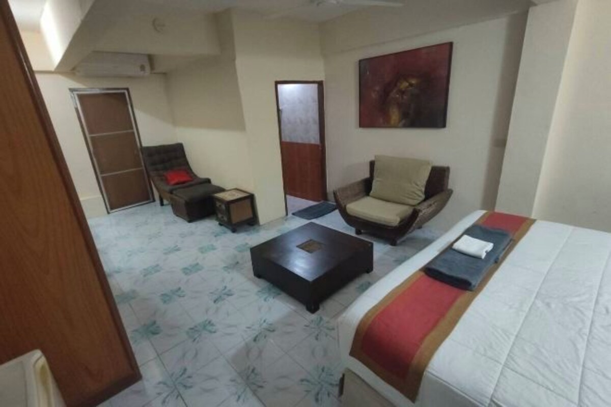 A room with a bed, a chair, a small table, and a wardrobe.