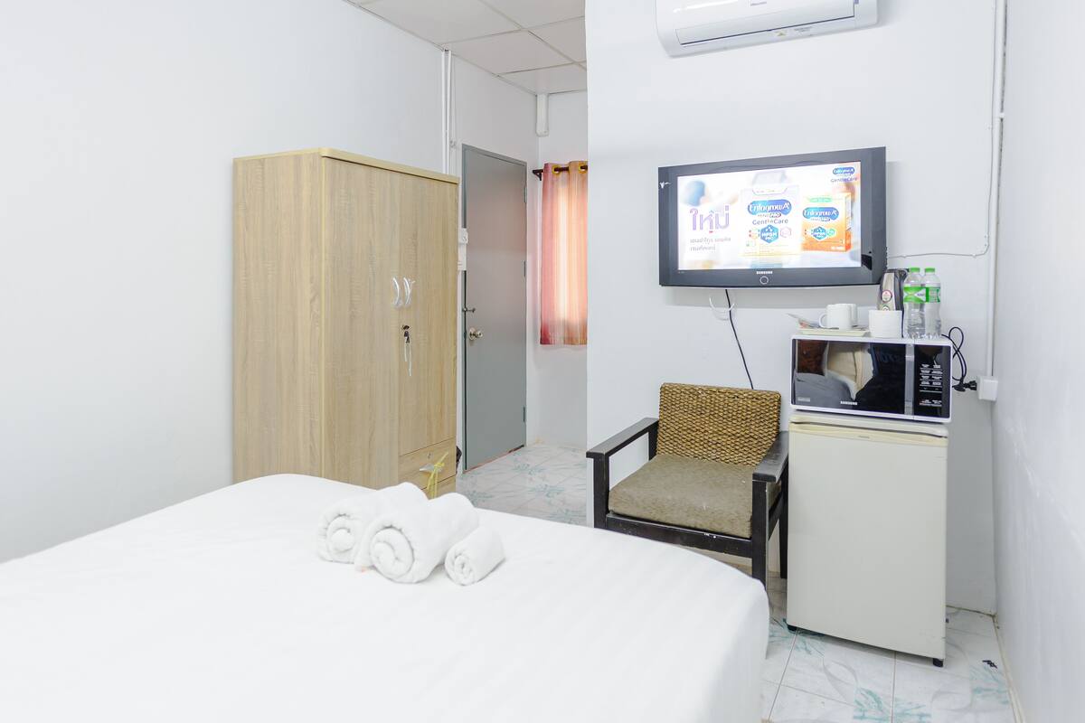 A hotel room with a bed, a TV, a minibar, and a wardrobe.