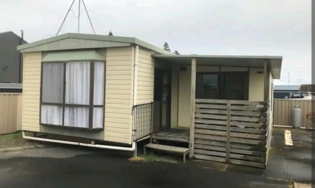 Une maison mobile de plain-pied avec un porche à l’avant et un petit garage attenant.