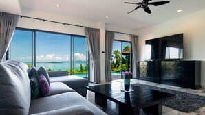 A modern living room with a large TV, a sofa, and a coffee table. - Picturesque 4br Cape Yamu  Pool Villa (Pa Klok)