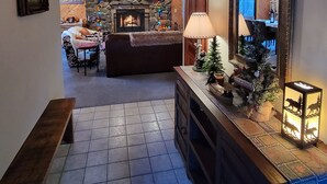 A cozy living area with a fireplace, a wooden ceiling, and a stone wall. - Four Seasons Getaway-Private Spa-Walk to Village and Pineknot Trailhead-King Bed (Big Bear Lake)