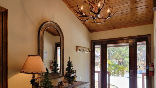 A wooden interior with a large mirror, a chandelier, and a door leading outside. - Four Seasons Getaway-Private Spa-Walk to Village and Pineknot Trailhead-King Bed (Big Bear Lake)