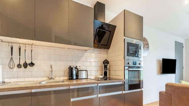 A modern kitchen with stainless steel appliances, a built-in oven, and a coffee maker. - Holiday Home in Goirle Near Efteling Park (Goirle)