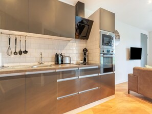 Una cocina moderna con electrodomésticos de acero inoxidable, horno empotrado y cafetera.