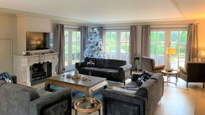 Ein modernes Wohnzimmer mit Kamin, einem großen Weihnachtsbaum und bequemen Sitzgelegenheiten.