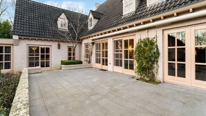 Ein Haus mit Ziegeldach, großen Fenstern und einem gepflasterten Innenhof.