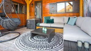 Interior acogedor de una cabaña de madera con un sillón colgante, un sofá, una mesita de centro y una alfombra estampada.