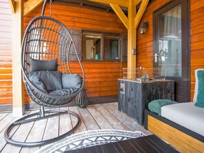 Una cabaña de madera con una silla colgante, una mesita y un sofá.