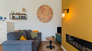Un salon avec un canapé, une table ronde, une bibliothèque et une cheminée.