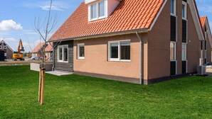 Ein modernes, zweistöckiges Haus mit rotem Ziegeldach, einem kleinen Dachfenster und einer Ziegel-Fassade.
