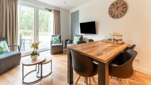 Ein modernes Wohnzimmer mit einem Holzesstisch, schwarzen Stühlen, einer Couch und einer großen Wanduhr.