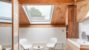 Eine moderne Küche mit Holzbalken, einem Oberlicht, weißen Schränken und einer weißen Arbeitsplatte.