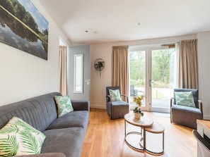 A modern living room with a grey sofa, two armchairs, a small round table, and a large window with curtains. - Holiday Home in Goirle With Sauna (Goirle)