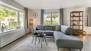Una sala de estar moderna con un sofá seccional gris, una lámpara de pie y una estantería.