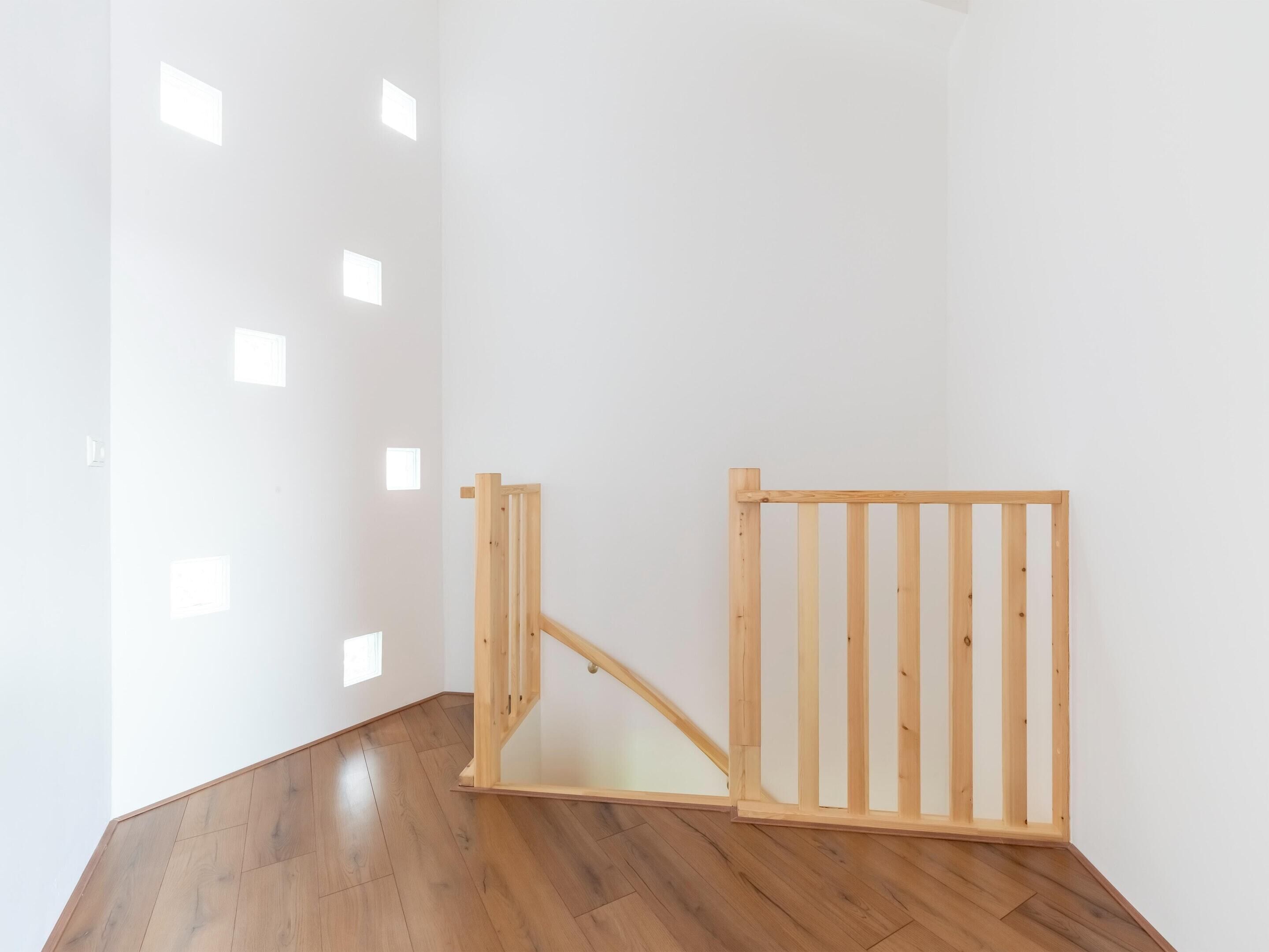 Una stanza con pavimento in legno, pareti bianche e un cancello di legno.