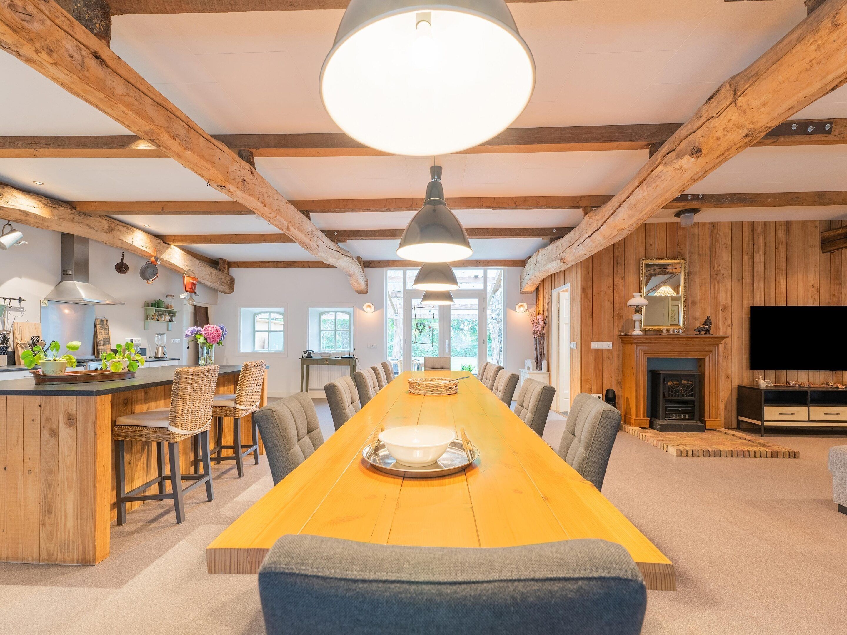 A spacious dining area with a long wooden table, multiple chairs, and a central chandelier.