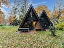 Un edificio moderno de forma triangular con fachada de vidrio, rodeado de follaje otoñal.