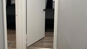 A hallway with a white door leading to a room with a bed and a black curtain. - Mankato’s Safe Haven (Mankato)