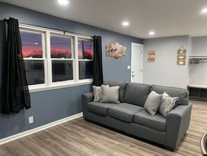 Relax in a stylish living room with a sofa against a wall, large window, and wall-mounted decorations.