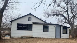 A small, single-story white building with a gabled roof, a front door, and two windows. - Mankato’s Safe Haven (Mankato)