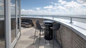 A terrace with a view of the sea, featuring a seating area with a sofa and chairs, and a round table. - Apartment in Scherpenisse by Oosterschelde (Scherpenisse)