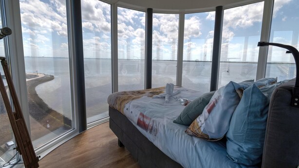 A bedroom with a large window overlooking a body of water and a dock. - Apartment in Scherpenisse by Oosterschelde (Scherpenisse)