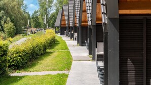 Een rij moderne gebouwen met een hellend dak, een verhard pad en een verzorgd gazon met heesters.