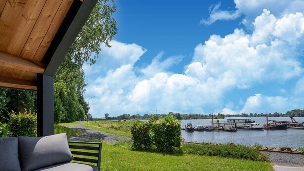 Een overdekt terras met uitzicht op een meer en boten.