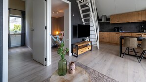 Een moderne woonruimte met een trap, een flatscreen televisie, houten kasten en een eethoek.