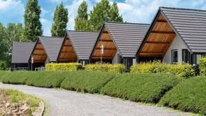 Een rij moderne gebouwen met een driehoekige kap, een grindpad ernaartoe en omringd door verzorgde beplanting.
