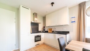 Una cucina moderna con mobili bianchi, un piano di lavoro nero e un tavolo da pranzo in legno con sedie.