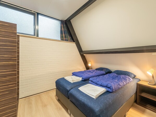 Relax in this cozy loft-style bedroom with a large bed, nightstand, and window offering a view of the outside.