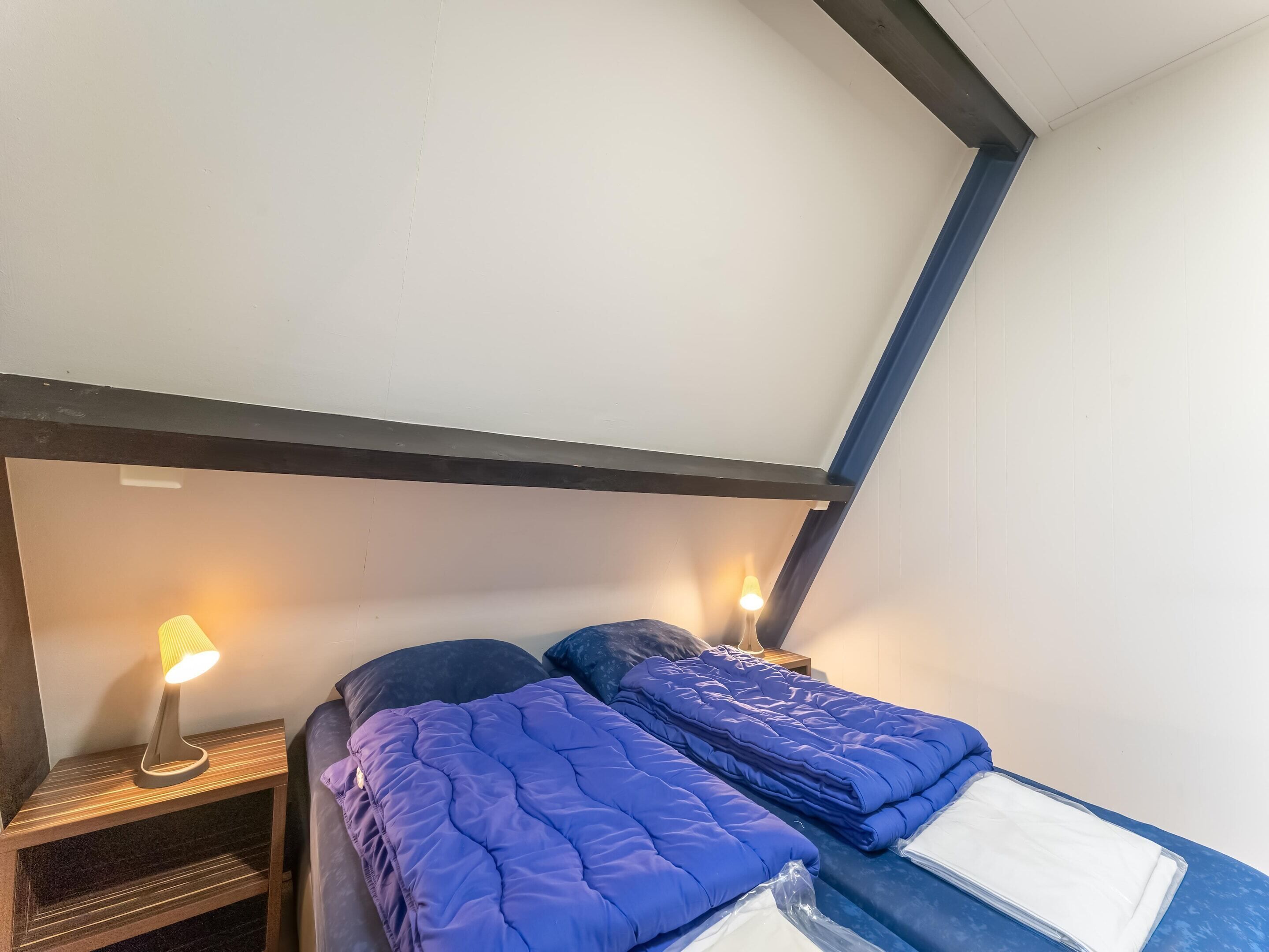 A bedroom with two beds, a nightstand, and a lamp.