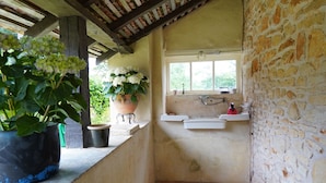 A narrow corridor with a tiled floor, a stone wall, a window with a sink, and potted plants. - Authentic 19th c Farmhouse  with heated pool fiber optic and air conditionné (Saint-Germain-des-Prés)