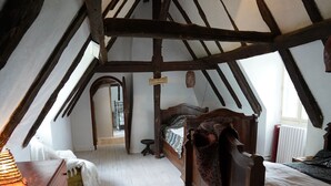 A bedroom with a sloped ceiling, wooden beams, a bed, a dresser, and a hanging light fixture. - Authentic 19th c Farmhouse  with heated pool fiber optic and air conditionné (Saint-Germain-des-Prés)
