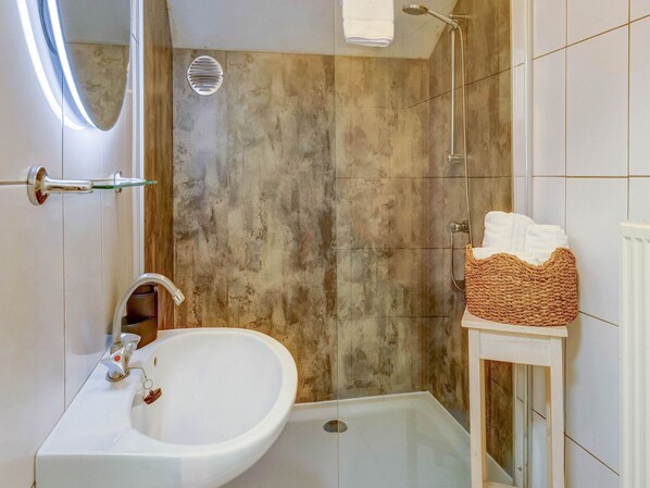 A bathroom with a white sink, a shower, and a towel rack.