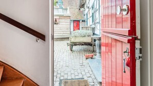 A narrow cobblestone street leading to a building with a red door and a wooden cart. - Beautiful Holiday Home in Voerendaal (Voerendaal)