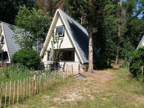 A small, single-story house with a sloped roof, surrounded by a wooden fence and dense trees. - Holiday Home in Eerbeek With Terrace (Eerbeek)
