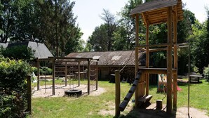 Uma área de recreação infantil com estruturas de madeira e cobertura metálica.