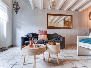 A modern living room with a dark blue sofa, a white armchair, and a round wooden coffee table with drinks. - Pet-friendly Country Escape (Voerendaal)