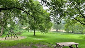 A picnic area with a wooden table and a swing set in a grassy park. - Attractive Apartment in South Limburg (Klimmen)