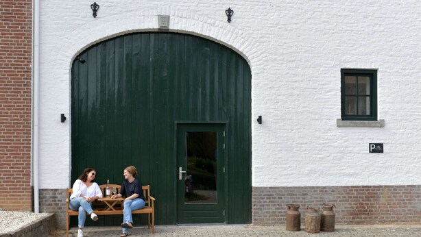 A building with a large green door and a small window. There is a bench outside the door. - Attractive Apartment in South Limburg (Klimmen)