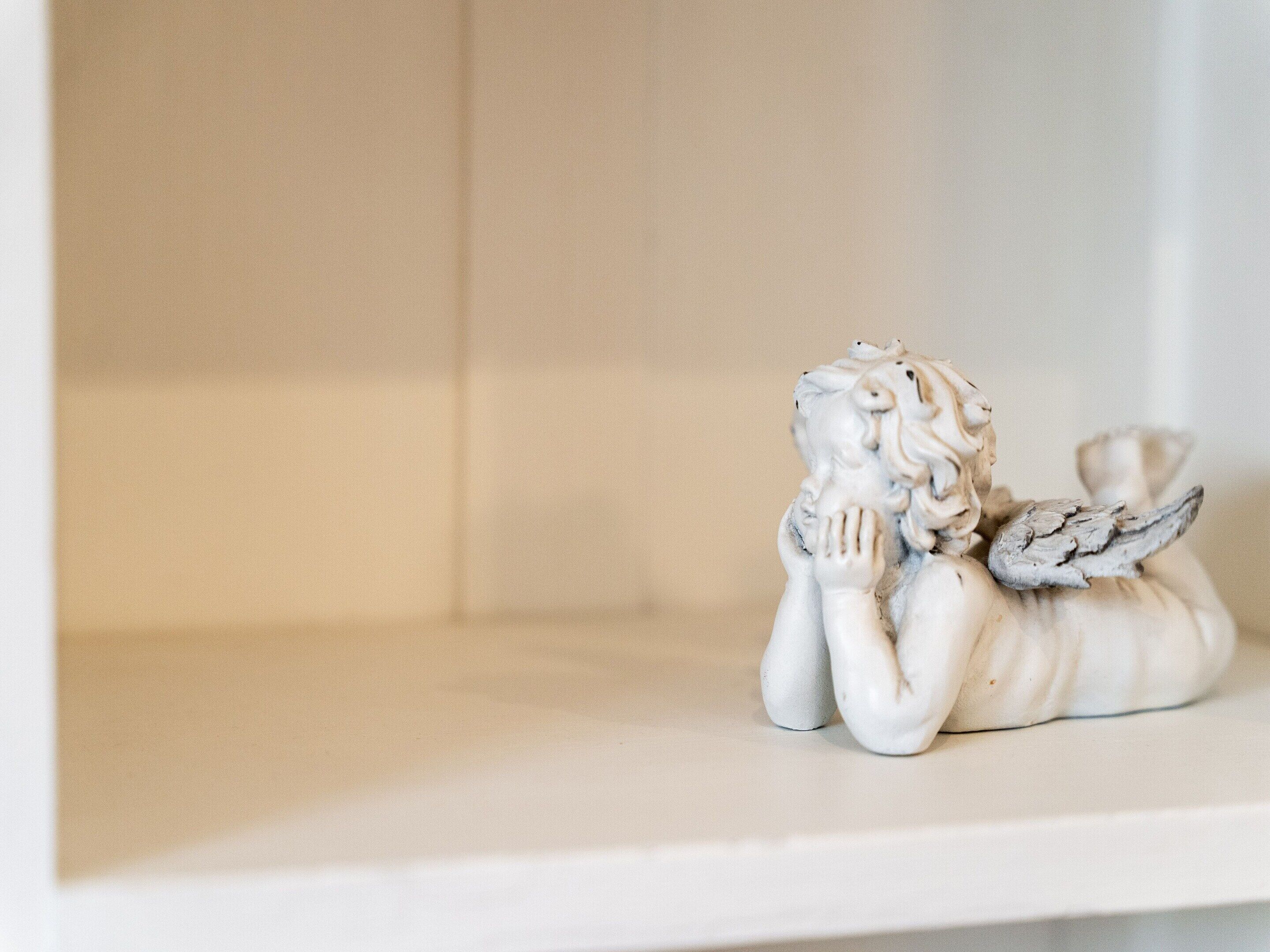 En hvid reol med en lille engel figur.